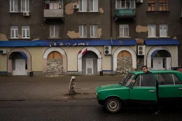 Menschen schieben ein liegengebliebenes Fahrzeug an einem stillgelegten Restaurant vorbei. - © Bram Janssen/AP/dpa
