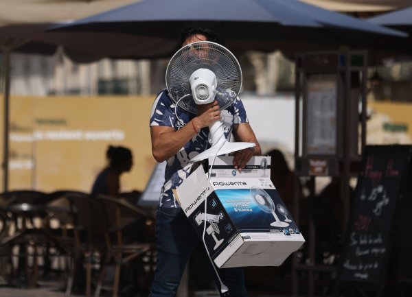 Ein Mann trägt einen Ventilator, während er bei 38 Grad Celsius über die Place de la Comedie in Montpellier geht. - © Gao Jing/XinHua/dpa