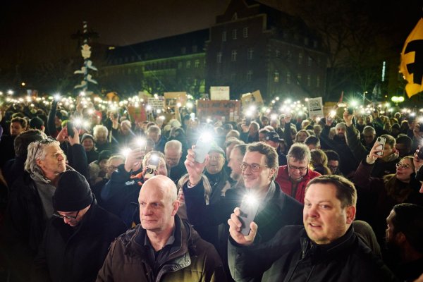 NRW-Ministerpräsident Hendrik Wüst hält bei einer Demo gegen die AfD ein Handylicht hoch. - © Bernd Thissen/Land NRW/dpa