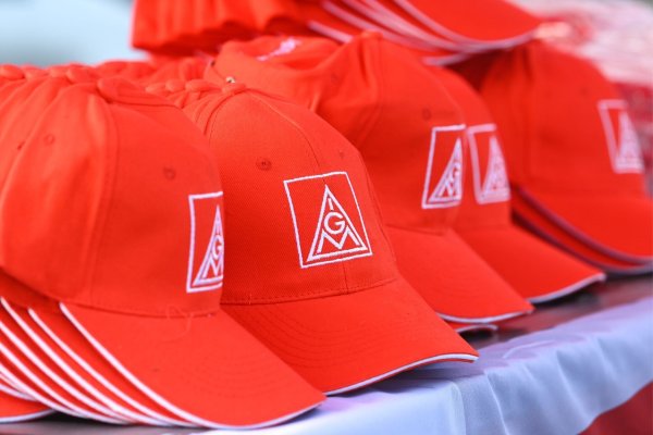 Mützen mit dem Logo der IG Metall liegen auf einem Tisch. - © Heiko Rebsch/dpa/Symbolbild
