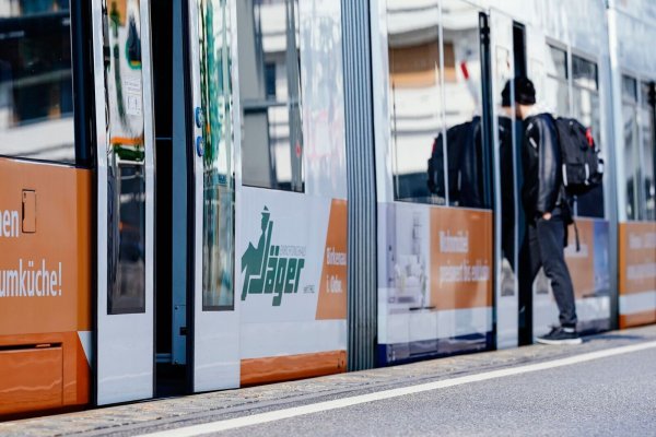 Ein junger Mann steigt an einer Straßenbahnhaltestelle in eine Straßenbahn ein. - © Uwe Anspach/dpa/Symbolbild