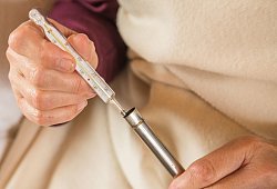 Frau h&auml;lt ein Fieberthermometer mit Quecksilber in den H&auml;nden - Christin Klose/dpa-tmn