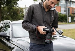 Mann schaut nach dem Fotografieren seines Autos auf Kameradisplay - Christin Klose/dpa-tmn