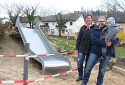 Kitaleiterin Stefanie Blome (links) und die Vorsitzende des Kita-Fördervereins Nicole Reker mit Sohn Mats (2) stehen vor der gesperrten Rutsche in der Kita "Pusteblume". Die Kinder haben die Rutsche in den vergangenen Jahren fast komplett unterhöhlt, sodass sie nun vom Bauhof gesperrt werden musste, da unter anderem der Fallschutz nicht mehr gegeben ist. Zudem hält ein Igel dort derzeit seinen Winterschlaf. - Michaela Weiße