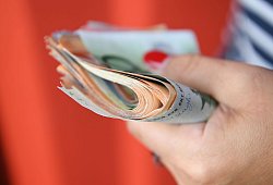 Frau h&auml;lt ein B&uuml;ndel Geldscheine in der Hand - Robert Michael/dpa-Zentralbild/dpa-tmn