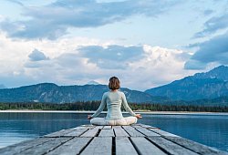 Eine Frau sitzt auf einem Steg und meditiert - Daniel Ingold/Westend61/dpa-tmn