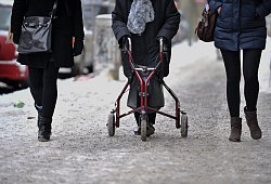Ein Frau geht mit Rollator auf einem schneebedeckten Gehweg - Paul Zinken/dpa/dpa-tmn