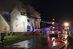 Brand: Einsatzkräfte der Feuerwehr Blomberg stoßen Löcher in das Dach einer ehemaligen Gaststätte in Istrup, damit der Rauch abziehen kann. - Jana Beckmann