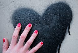 Frauenhand berührt ein auf die Wand gesprühtes Herz - Inga Kjer/dpa/dpa-tmn