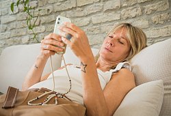 Frau mit Smartphone im Wohnzimmer - Christin Klose/dpa-tmn