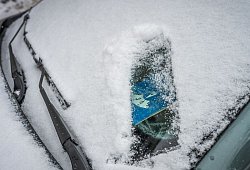 Eine Parkscheibe hinter einer verschneiten Windschutzscheibe - Zacharie Scheurer/dpa-tmn