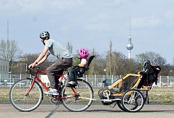 Mann transportiert Kinder mit dem Fahrrad und einem Anhänger - Andrea Warnecke/dpa-tmn