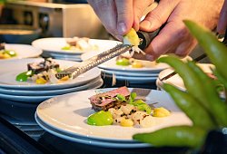 Koch reibt Zesten der Zitrusfrucht Buddhas Hand &uuml;ber ein Men&uuml; - Christin Klose/dpa-tmn