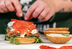 Eine Köchin belegt einen Burger mit veganem Fischersatz - Daniel Karmann/dpa/dpa-tmn
