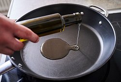 Mann sch&uuml;ttet Sonnenblumen&ouml;l in eine Pfanne - Annette Riedl/dpa/dpa-tmn