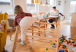 Ein zweij&auml;hriges Kind klettert im Wohnzimmer auf ein Spielger&auml;t - Julian Stratenschulte/dpa/dpa-tmn