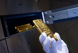 Mann legt einen Goldbarren in ein Schlie&szlig;fach eines Tresorraums - Sven Hoppe/dpa/dpa-tmn