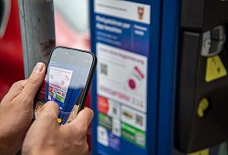 Ein Mann scannt den QR-Code einer Park-App mit einem Smartphone - Nico Tapia/dpa-tmn