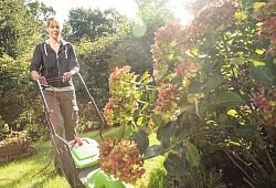 Frau mäht den Rasen im Garten - Christin Klose/dpa-tmn