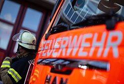 Feuerwehrmann steht neben einem Feuerwehrauto (Symbolbild) - Marijan Murat/dpa