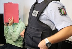 Die Angeklagte verdeckt beim Prozessauftakt ihr Gesicht mit einem roten Aktendeckel. - Holger Kosbab