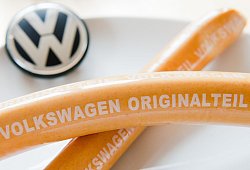 Zwei Currywürste mit der Aufschrift "Volkswagen Originalteil" liegen auf einem Teller mit VW-Logo. Die Streichung in einer Kantine ruft auch die heimischen Landwirte auf den Plan. - Julian Stratenschulte