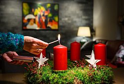 Eine Frau zündet eine Kerze auf einem Adventskranz an - Patrick Pleul/dpa/dpa-tmn