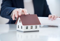 Ein Mann greift nach einem Modellhaus - Christin Klose/dpa-tmn