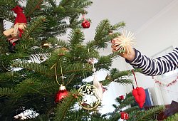Mädchen schmückt einen Weihnachtsbaum - Bodo Marks/dpa-tmn