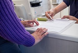 Arzthelfer &uuml;bergibt Patientin einen Anamnesebogen - Christin Klose/dpa-tmn