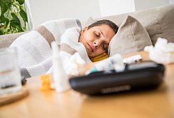 Eine Frau liegt krank auf einem Sofa - dpa