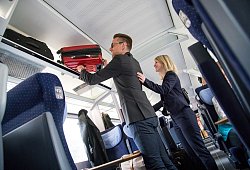 Ein Mann verstaut sein Gep&auml;ck &uuml;ber seinem Sitzplatz im Zug - Christin Klose/dpa-tmn