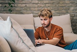 Ein Mann am Laptop auf einer Couch - Zacharie Scheurer/dpa-tmn