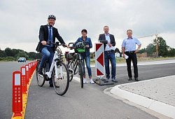 Bürgermeister Jürgen Schell, Conny Hagen von der Lebenshilfe sowie Tobias Fischer und Dietmar Stölting von „Straßen.NRW"  (von links) präsentieren am 22. Juni auf einem Pressetermin, dass sie mit dem Provisorium während der Bauzeit mehr Sicherheit für Radler bieten. - Katrin Kantelberg