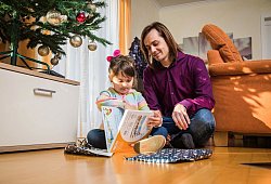 Vater packt mit seiner Tochter Weihnachtsgeschenke aus - Christin Klose/dpa-tmn