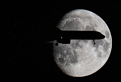 Ein Flugzeug fliegt am Mond vorbei - Boris Roessler/dpa