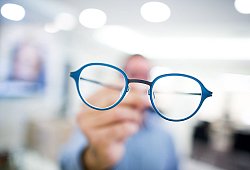 Optiker hält eine Brille in der Hand - Rolf Vennenbernd/dpa/dpa-tmn