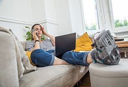 Eine Frau mit einem Gehgips am Fuss auf einer Couch - Christin Klose/dpa-tmn