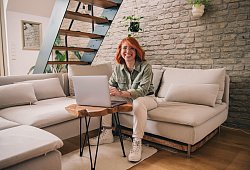 Eine Frau am Laptop sitzt auf einem Sofa - Zacharie Scheurer/dpa-tmn