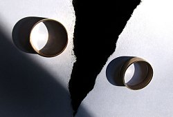 Zwei getragene Eheringe liegen auf einem zerrissenen Papier - Karl-Josef Hildenbrand/dpa