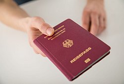 Ein junger Mann h&auml;lt seinen Reisepass in der Hand - Christin Klose/dpa-tmn