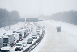 LKW und Autos stehen bei Schnee im Stau - Fabian Strauch/dpa/dpa-tmn