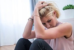 Junge Frau sitzt traurig auf dem Fu&szlig;boden einer Wohnung - Christin Klose/dpa-tmn