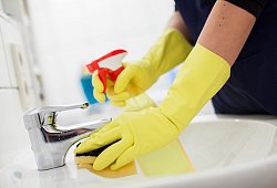 Person putzt ein Waschbecken im Badezimmer - Christin Klose/dpa-tmn