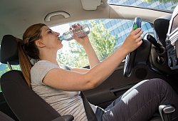 Frau trinkt während der Autofahrt aus einer Wasserflasche - Christin Klose/dpa-tmn