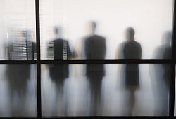 Personen stehen hinter eine Glasscheibe in einem B&uuml;ro - Sebastian Kahnert/dpa/dpa-tmn