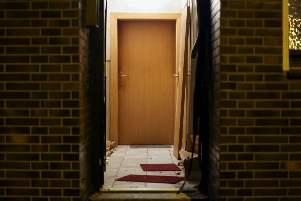 Nach einem Polizeieinsatz ist die Haustür eines Mehrfamilienhauses stark beschädigt. - © Christoph Reichwein/dpa