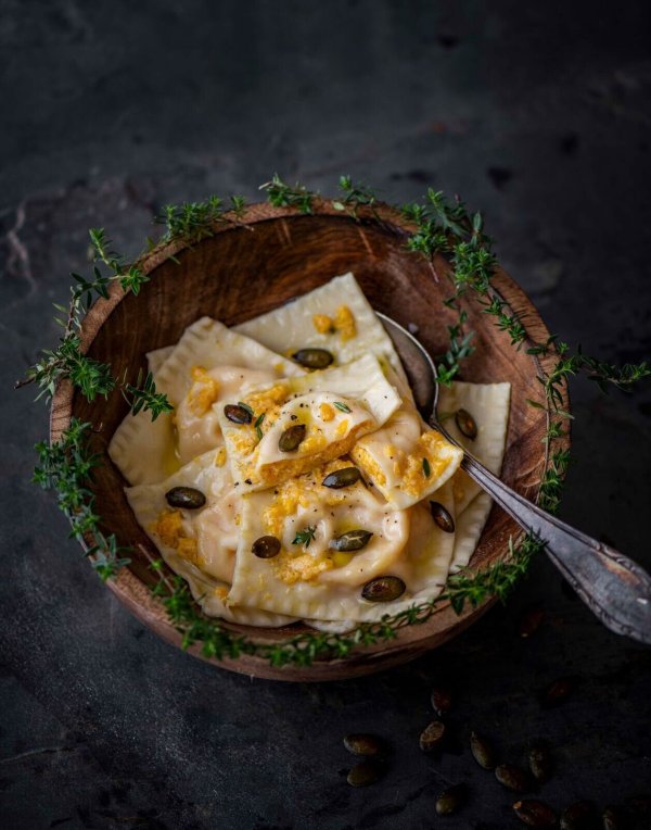 Einen Teil der Kürbis-Ricotta-Mischung wird zum Servieren über die Ravioli verteilt und mit gerösteten Kürbiskernen und Parmesan getoppt. - © Valerie Hammacher/ars vivendi/dpa-tmn