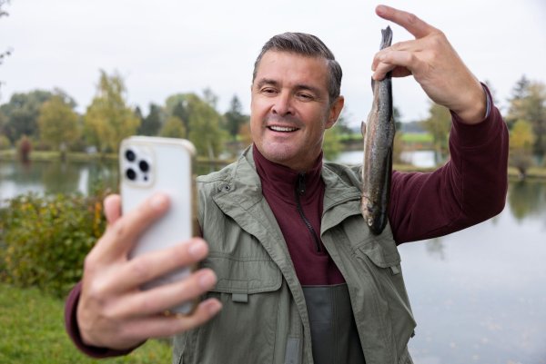 Stolz posiert Wirt Jo (Christian K. Schaeffer) für ein Selfie, das seinen erfolgreichen Fischfang dokumentieren soll. - © Markus Sapper/ZDF/dpa