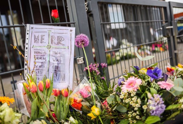 Ein Zettel mit dem Text «Herr vergib ihnen, denn sie wissen nicht, was sie tun» steckt zwischen Blumen und Kerzen vor dem Eingangsbereich eines Gemeindehauses der Zeugen Jehovas. - © Christian Charisius/dpa